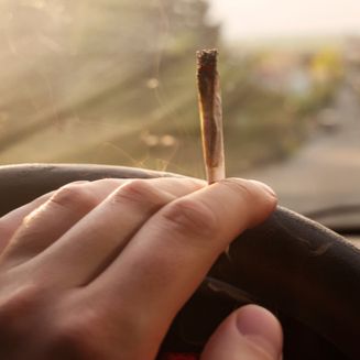 One hand on wheel of car with joint